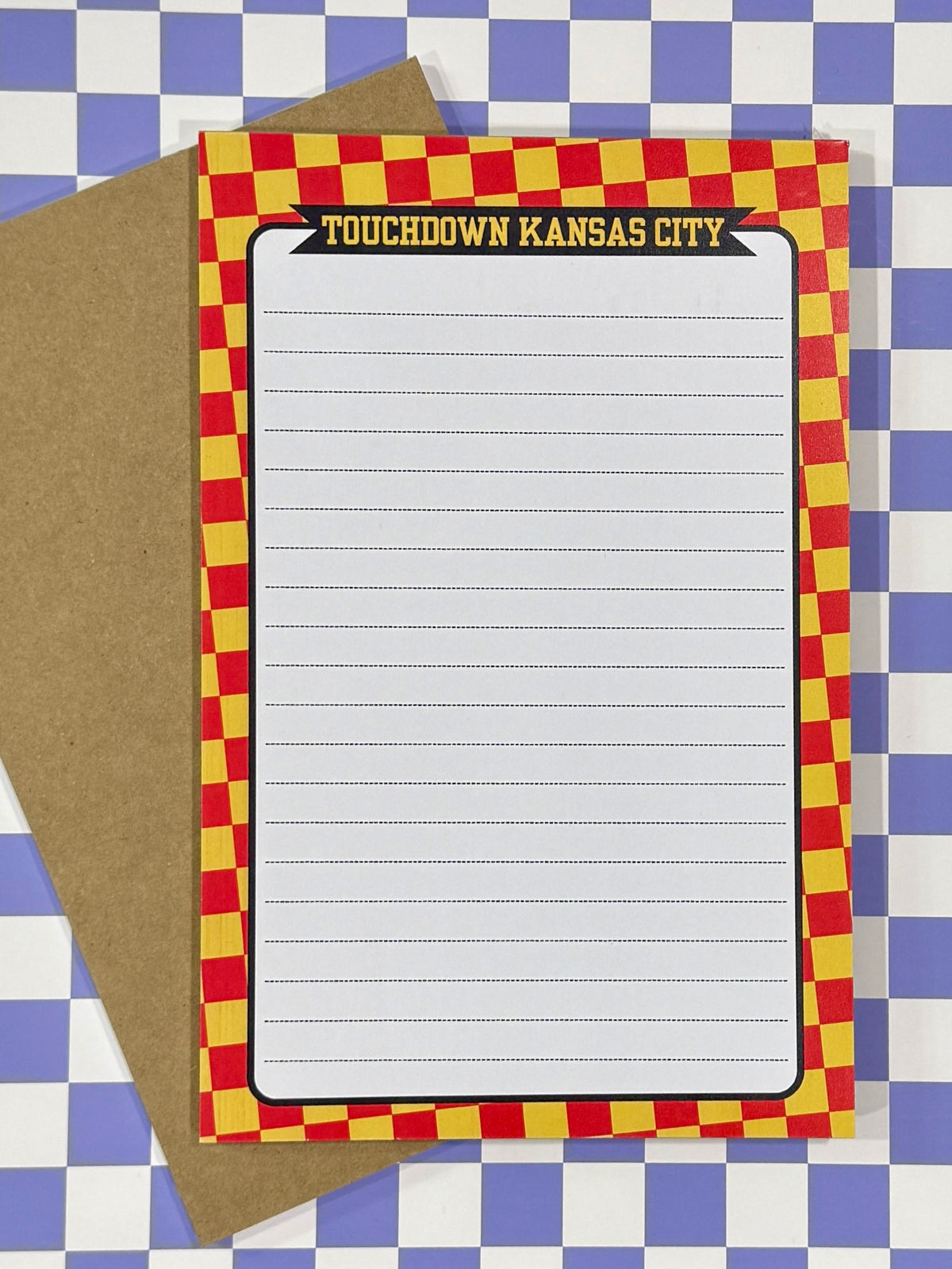 Note pad with red and yellow checkered border on a blue and white lined background with text “touchdown Kansas City” at the top