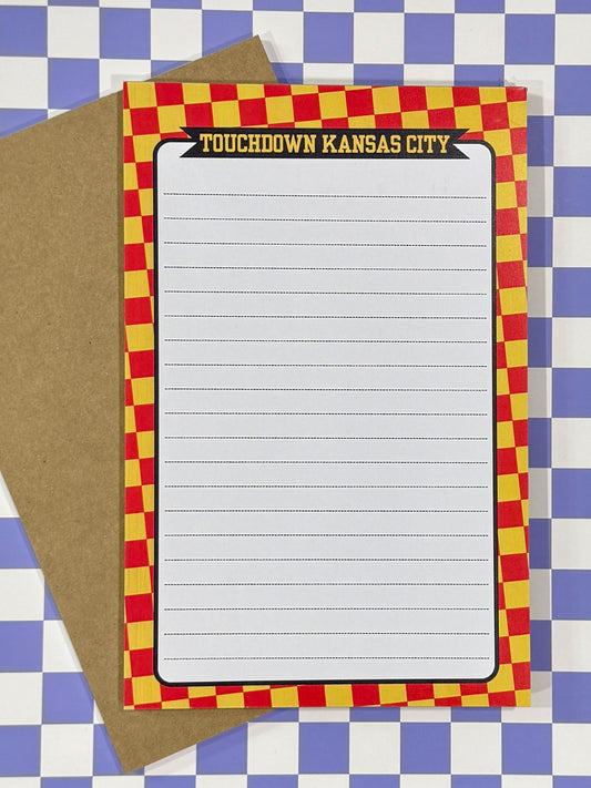 Note pad with red and yellow checkered border on a blue and white lined background with text “touchdown Kansas City” at the top